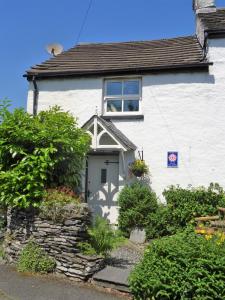 a white house with a window and some bushes at Burnthwaite Cottage in Windermere