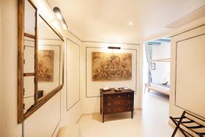 a hallway with a table and paintings on the walls at Algilà Ortigia Charme Hotel in Siracusa