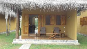 ein Haus mit einem Tisch, Stühlen und einem Strohdach in der Unterkunft Happy Man Village in Bentota