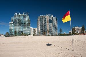 a yellow and red flag on a beach with tall buildings at Reflection on the Sea in Gold Coast