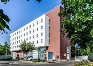 un grande edificio bianco e rosso con auto parcheggiate fuori di ibis budget Augsburg City a Augusta (Augsburg)