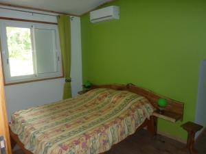 Dormitorio verde con cama y ventana en La Pointe au Corail, en Sainte-Rose
