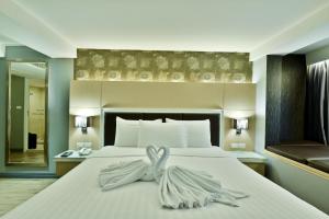 una camera da letto con un letto e un asciugamano sopra di Prestige Suites Nana a Bangkok