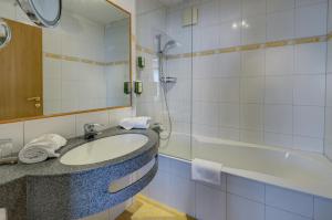 a bathroom with a sink and a tub and a mirror at Vötter's Hotel in Kaprun
