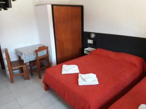 - une chambre avec un lit rouge et 2 serviettes dans l'établissement Hosteria Quime, à La Lucila del Mar