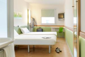 um quarto de hospital com um sofá e um lavatório em ibis budget Augsburg City em Augsburg