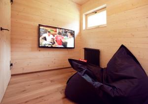 een kamer met een tv in een houten muur bij CASALPIN Chalets in Brand