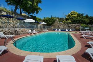 a swimming pool with chairs and umbrellas next to a stone wall at Le Moulin de Sournia in Sournia