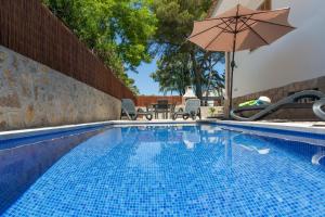 a large swimming pool with an umbrella and chairs at Mar Blava House in Playa de Muro