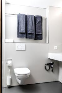 een witte badkamer met een wit toilet en handdoeken bij Revier Mountain Lodge Lenzerheide in Lenzerheide