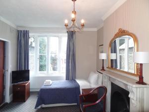 a bedroom with a bed and a fireplace and a mirror at Regency House Hotel in London