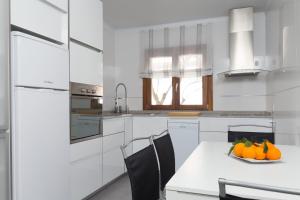 a white kitchen with a plate of fruit on a table at Verdera in Playa de Muro