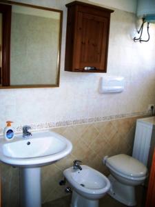 a bathroom with a sink and a toilet and a mirror at I Villini di Baia Delle Mimose in Badesi