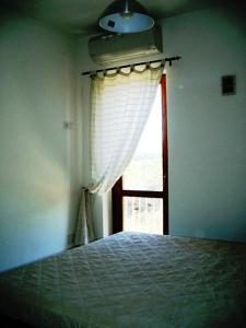Schlafzimmer mit einem Bett und einem Fenster in der Unterkunft I Villini di Baia Delle Mimose in Badesi