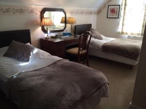 a hotel room with two beds and a desk and a mirror at Beachy Rise in Eastbourne