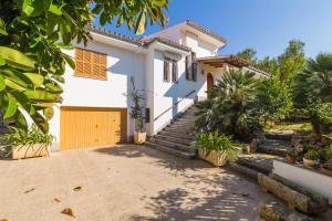 a white house with a yellow garage at Franciscus in Playa de Muro