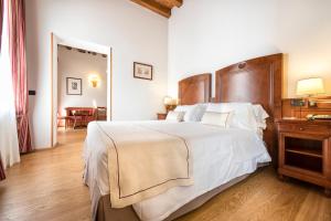una camera da letto con un grande letto bianco con testiera in legno di Hotel Villa Malaspina a Castel d'Azzano