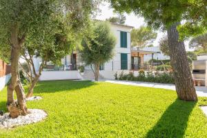 a yard with trees in front of a house at Casa Marian in Can Picafort