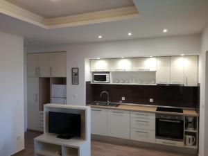 a kitchen with white cabinets and a tv in it at Apartments Lipić in Posedarje
