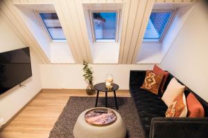Habitación en el ático con sofá y mesa en Home Again Apartments Nygata 1 en Stavanger