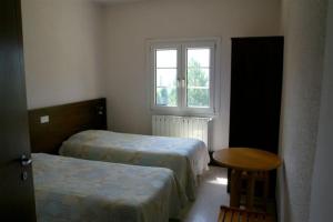 オロンにあるLe Collet d'Auronのベッド2台、テーブル、窓が備わる客室です。