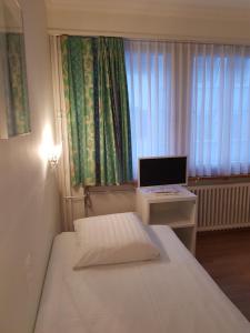 Habitación pequeña con cama y escritorio con ordenador. en Hotel Elite, en St. Gallen