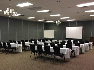 a conference room with white tables and chairs and a screen at Hope Hotel and Richard C. Holbrooke Conference Center in Fairborn