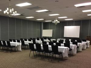 una sala de conferencias con mesas y sillas blancas y una pantalla en Hope Hotel and Richard C. Holbrooke Conference Center, en Fairborn