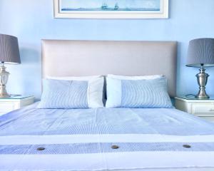 a bedroom with a bed with blue walls and two lamps at Hightide Apartment in Amanzimtoti