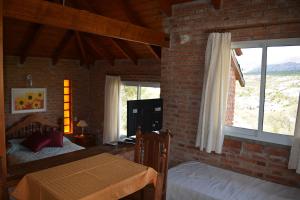 a bedroom with two beds and a brick wall at Cabañas Del Rio in Mina Clavero