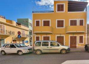 two cars parked in front of a yellow building at Appartamenti Il Gabbiano in Lampedusa