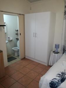 1 dormitorio con baño con aseo y 1 cama en MulMas Guest House, en Pretoria