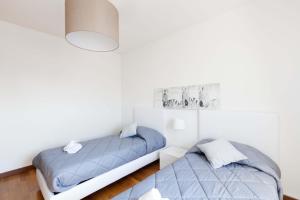 two beds in a room with white walls at Attico Ai Cedri in Verona