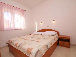 een slaapkamer met een bed met een houten hoofdeinde en een raam bij Apartment Maslina-2 by Interhome in Srima