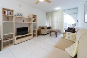 a living room with a couch and a tv at Pissouri Beach Apartments in Pissouri