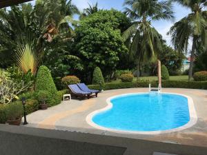 a swimming pool in a garden with a bench next to it at Peaceful homestay in Rawai Beach
