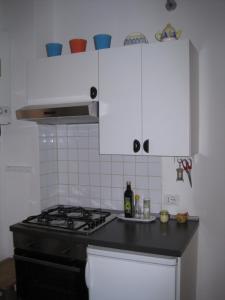 a kitchen with a stove and white cabinets at Una Porta sul Porto Antico in Genova