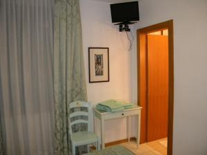 um quarto com uma mesa, uma cadeira e uma televisão em Hotel Adua em Veneza