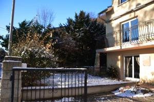 a fence in front of a house with snow on the ground at Le Croissant de Lune in Ingersheim