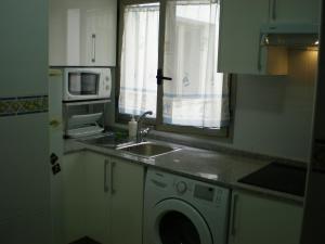 a kitchen with a sink and a washing machine at A Un Paso Del Mar in Arinaga