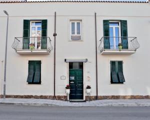 un edificio blanco con ventanas con persianas verdes y una puerta en Carrer Dels Horts, en Alghero