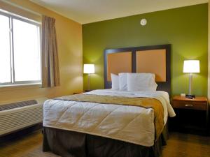a bedroom with a large bed with green walls and a window at Suburban Studios Jackson North in Jackson