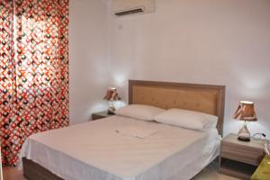 - une chambre avec un lit avec deux lampes et un rideau dans l'établissement Oslo Apartments - Albania, à Vlorë