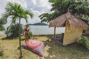 a woman in a bikini standing next to a palm tree at Palmyra Indah Bungalows in Sekotong