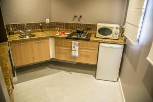 a small kitchen with a microwave and a refrigerator at Hotel Cosmopolitan Praia Flat in Santos