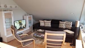 トラフェミュンデにあるPEMATRA Ferienwohnung Unterm Dachのリビングルーム(黒いソファ、椅子付)
