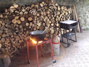 a grill and a pan on a table next to a pile of wood at Hudi-Lak Vendégház in Háromhuta