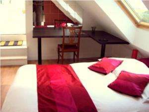 1 dormitorio con cama con almohadas rojas y escritorio en Auberge An Douar, en Quéven