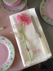 a pink flower sitting on a napkin with a knife at B&B Het Postenhofje in Puiflijk