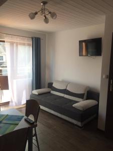 a living room with a couch and a tv at Apartamenty i pokoje "U Dawida" in Mrzeżyno